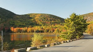 Early morning, panning view of Beaver Dam Pond, Acadia's Park Loop Road, and nearby mountains covered in Autumn foliage; Acadia National Park, Maine.