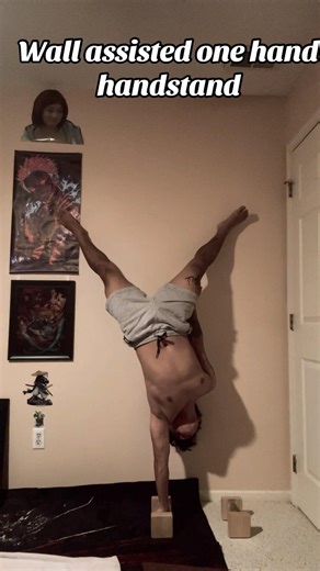 Wall assisted one hand handstand