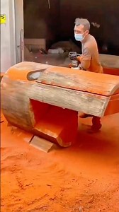 carving large wooden log with electric tool shaping smooth surface and forming creative furniture