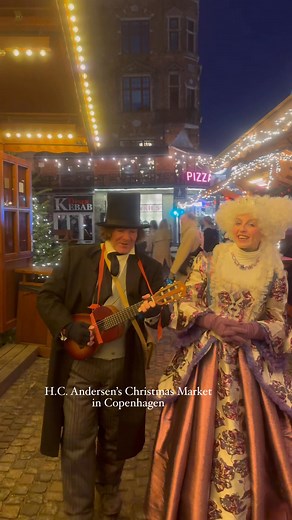 Fairytale Christmas Singing at H.C. Andersen Market, Copenhagen 📸 My Danish Experience 📝 Today at H.C. Andersen’s Christmas Market near the beautiful Caritas Fountain, I came across a magical moment — a man playing guitar and a woman singing, both dressed in enchanting H.C. Andersen fairytale costumes. Their voices added pure Christmas magic to the whole market atmosphere. I asked them if I could share their performance on my Facebook page “My Danish Experience,” and they happily agreed. They 