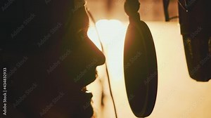 Close up face silhouette singer sings hiphop at recording room at orange light. Records vocal on studio microphone. Solo, headphones, music, mouth, broadcast, musician. Slow motion