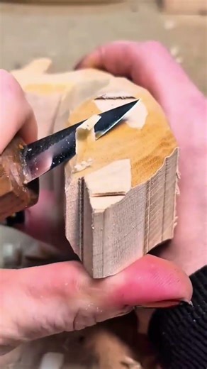 Carving and shaping a small wooden figure with a sharp knife to create detailed textures and forms
