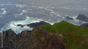 Bird's-eye view of Malin Head cliff edge with aerial rise over rugged coastline