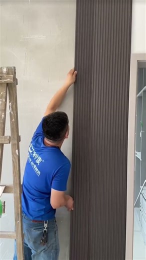 the process of installing striped and plain boards on the walls in the living room of the house