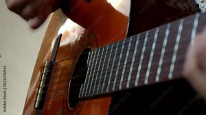 Asian teen's hands play guitar, developing musical talent and skill. Indonesian teen learning guitar, unlocking musical potential through practice. Building musical skills and confidence.