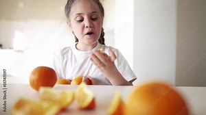 girl child eating oranges. happy family fruit healthy food kid concept. little girl daughter eating dream oranges at the table in the kitchen indoors. juicy fruits oranges are for a healthy diet