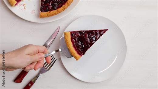 The hostess takes a piece of homemade cherry pie and puts it on a plate. Top view.