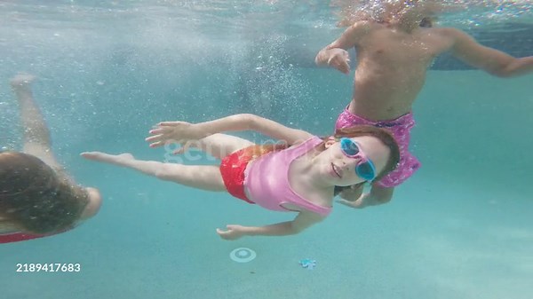 Children diving into a swimming pool and enjoying swimming on a...