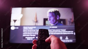 Man watches smart TV and uses remote control. Person controls TV using a modern remote control.
