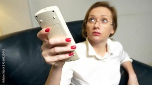A business woman in a white blouse and red manicure unbuttons her shirt, and turns on the air conditioner with a remote control. close-up
