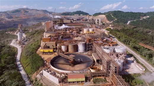Barrick Gold mine complex showing large scale concentrators, tanks, pipes, steam vents, and surrounding hills in Cotuí Republic. Aerial flyover | Premium Stock Video Footage