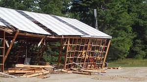 With Bates' new boathouse nearly ready to open, the college's original facility — a minimalist, barnlike structure from 1988 — was knocked down yesterday morning. Bates rowing coach Peter Steenstra was on hand for the demolition. "I'm proud of what we did with so little," Steenstra said. "And now it's amazing how so little can somehow seem like so much." Operating the power shovel that took down the old house was Walter Davenport, an employee of the Wayne, Maine, excavation firm C.H. Stevenson. 