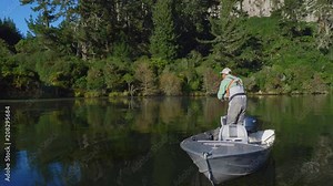 Fly fisherman casting his line from a boat in Lake Whakamaru in New Zealand