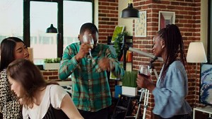 Multiracial school colleagues organizing apartment party, enthusiastically dancing to electronic music in brick wall home. Mates enjoying time spent together, busting into animated dance moves