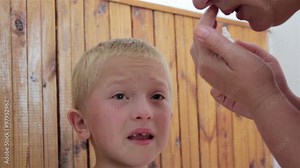 drip into the eyes/mother treats her son dripping eye medication eye