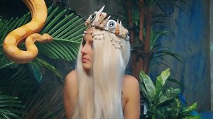 Close-up art portrait woman with snake. Nagga goddess touches white milk Boa constrictor. Fantasy asp girl blonde long hair, looks at serpent. Lady goth vampire queen viper. Backdrop green palants. 4k