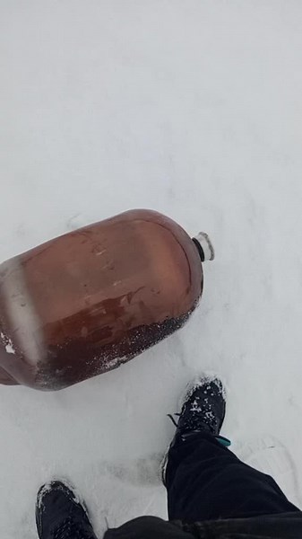 Curious Brown Glass Bottle Rolls in Snowy Landscape