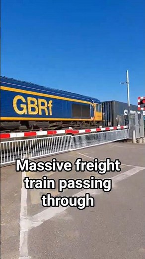 Class 66 Freight Train Hauling Containers Through Level Crossing