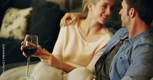 Making time for romance. Happy young couple having wine on the sofa at home. Married man and woman in love in a romantic moment talking and having drinks together