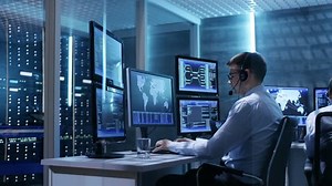 Panorama Shot of System Control Room with Three Technical Controllers Working at Their Workstations With Multiple Displays. Shot on RED EPIC-W 8K Helium Cinema Camera.