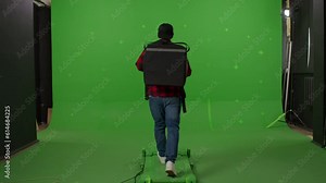 Back view of pizza delivery man with a thermal backpack with food walks along a virtual street and on a green background. copy space on chromakey