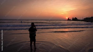 Young Indian woman walking on the Goa beach against the setting sun background. Indian female tourist walks along the beach at sunset.