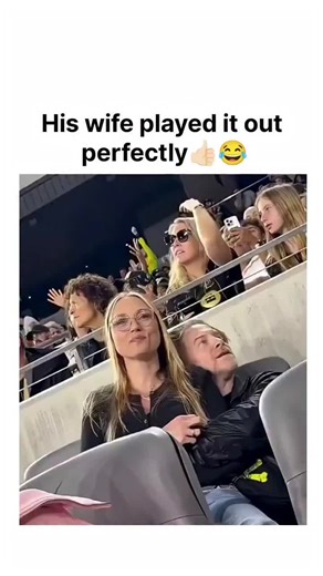golmal on Instagram: "The viral video captures actor Seth Green and wife Claire Forlani on the kiss cam at a January 2026 LA Galaxy match in BMO Stadium, where a jumbotron text glitch repeats "and his wife" to hilariously imply polygamy. Forlani's over-the-top reaction—covering her face in mock horror while Green grins—perfectly sells the bit, turning a technical error into a comedic goldmine that resonates with viewers' love for celebrity awkwardness. With 230k+ likes and 19M views in 24 hours,