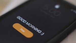 Good morning alarm clock on the phone , close-up. Hand tapping stop.