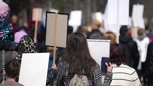 A lot of group activists feminist politics protest go city street. Hands hold banners. Sign posters against demonstrate. Crowd feminism protesters walk with placards. Rally activism. Riot action 2022