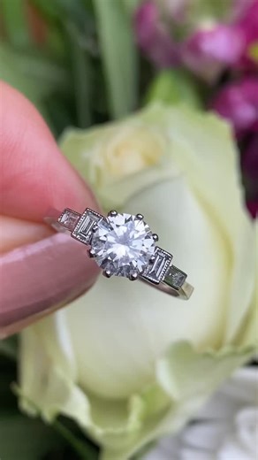 Philip Lloyd Jewellers on Instagram: "💎 A Beautiful Art Deco Classic ✨ This Art Deco Style Diamond Solitaire is a breathtaking blend of timeless elegance and crisp geometric detail. At its centre sits a stunning 1.80ct Brilliant Cut Diamond, set in a traditional eight claw setting. The central stone is exceptionally clean, bright and lively, with no marks visible even under a jeweller’s loupe. It is approximately J/K colour and VS clarity, offering outstanding sparkle and fire. On either side, 