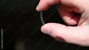 finger and thumb compressing a metal spring Stock Video