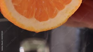 squeeze orange juice. sliced orange fruit with drops of juice falling from it in slow motion. Close Up macro shot.