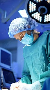 Female surgeon focused on operational spot using metal forceps and thread. Low angle view at the doctor finishing the surgery. Vertical video.
