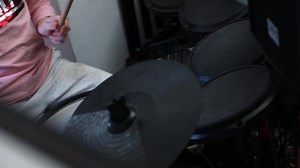 Teenage girl learning how to play drums in a home studio.