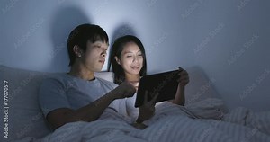 Couple using tablet computer on bed at night Stock Video