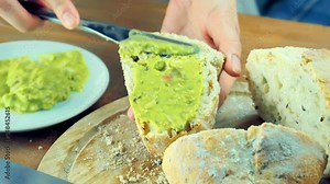 spread smashed avocado on freshly baked bread with a knife