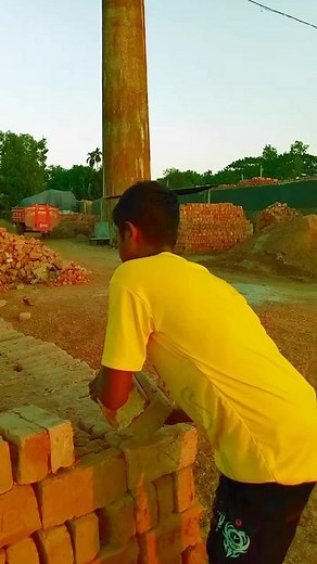 Young Male Balances and Lifts Bricks at Construction Site