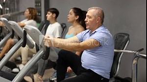 Concentrated elderly man working out on stationary bicycle in gym. Concept of healthy lifestyle of senior generation