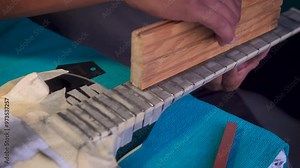 Luthier repairing an electric guitar, fret grinding, fretboard sanding and polishing, musical instrument workshop