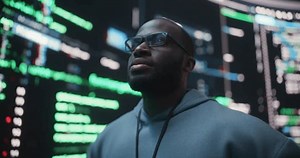 Portrait of Young Black Man Looking at Big Digital Screens Glitching While Displaying Code Lines. Worried Professional Programmer Fixing a Bug, Dealing with Crashing System, Thinking of Solutions