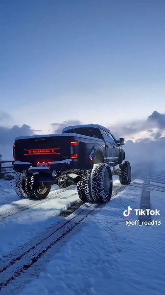 This is a video of a shiny black Ford Super Duty truck, likely a F-250 or F-350, with a massive lift kit and huge tires, driving down a highway. The video is stylized with a cinematic feel, and the truck looks very impressive.#Ford #SuperDuty #F250 #F350 #LiftedTrucks #TruckLife #CustomTrucks