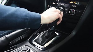 Female hand shifts gears. Automatic transmission, automatic gear shift, is moved from P to D. Park to Drive