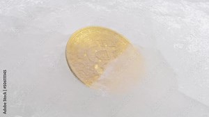Defrosting a golden coin with a bitcoin symbol on it close up. Macro time lapse