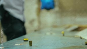 Empty pistol bullet shells dropping and impacting wooden table in a shooting range. Man is shooting with 9mm gun in the background. Close up, selective focus and copy space.