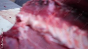 A cook in uniform and special gloves cut an amazing giant bluefin tuna with a sharp knife on a restaurant work table, close-up.
