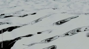 A close-up view of a shiny silver liquid showing a highly reflective, rippling surface. The smooth metallic texture creates an abstract pattern with fluidly flowing shapes. The lighting enhances the Stock Video