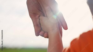 Helping hand. Mom holds baby by hand. Family teamwork. Happy kid holds mom hand. Family in park. Family team. Happy mom with baby. Happy kid. Family walk in park at sunset. Teamwork and helping hand