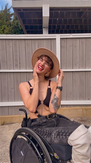 Aly Corvin on Instagram: "Genuinely wish I would have felt brave enough to do this sooner but I know I’m right where I’m meant to be and extremely lucky to have figured it out this early in life! 🫶🏼✨ Take the leap babe. Alt text: a woman sits in a wheelchair and talks to the camera outside with a grey wooden fence right behind her. She has red lipstick grey baggy jeans and a black cut-out body suit with a leather jacket on. Captions are on screen for accessibility. #Wheelchair #Wheelie #Crows 