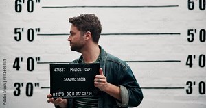 Man, criminal and outlaw with sign for mugshot, violation or investigation of arrest in prison. Portrait of young male person or thief with clothing, billboard or number for jail photo or picture