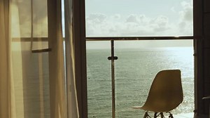 Beautiful View of the Sea Beach Sky Clouds Sun at Sunset from the Balcony Window of a Luxury Hotel Apartment. Sea in Sunlight. Terrace Chair and Amazing Ocean View. Sea View from the Window, Relax.
